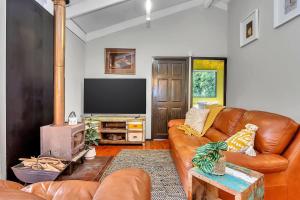 ein Wohnzimmer mit einem Ledersofa und einem Flachbild-TV in der Unterkunft Treetop Sanctuary - Serene Cottage near Mount Lofty in Upper Sturt