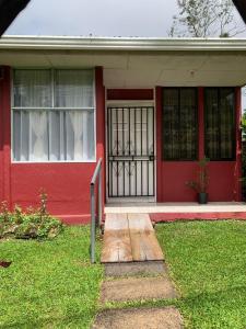 a red house with a red door with a gate at El Jardín de Tere in Bijagua