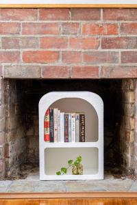 a white shelf with books and a brick wall at Oaklight Haven - Minutes to Geelong Waterfront & CBD in Hamlyn Heights