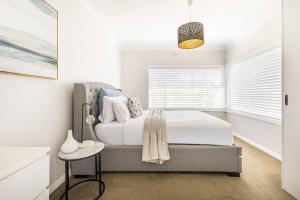 a white bedroom with a bed and a window at Oaklight Haven - Minutes to Geelong Waterfront & CBD in Hamlyn Heights