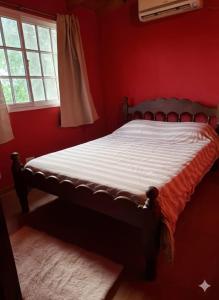 ein rotes Schlafzimmer mit einem Bett in einem Zimmer mit einem Fenster in der Unterkunft Orión VGB in Villa General Belgrano