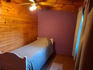 ein Bett in einem Zimmer mit einer Holzwand in der Unterkunft Orión VGB in Villa General Belgrano