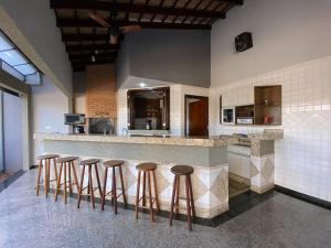 a kitchen with a counter with bar stools at Bela Casa Stella Maris - Casa de Carrara 01 in Andradina