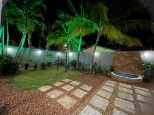 a garden at night with palm trees and a building at Bela Casa Stella Maris - Casa de Carrara 01 in Andradina