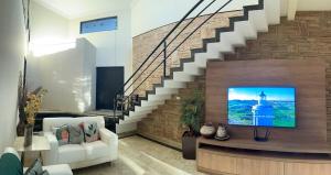 a living room with a tv and a staircase at Bela Casa Stella Maris - Casa de Carrara 01 in Andradina