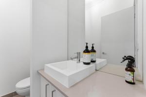 a white bathroom with two bottles of wine on a sink at Modern Family Retreat in Prime Williams Landing in Williams Landing +35 photos