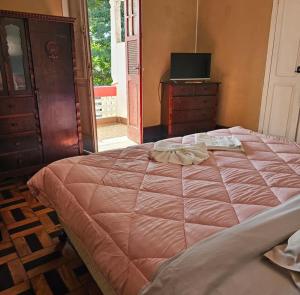 a bedroom with a large bed with a dresser and a television at Varzea Palace Hotel in Teresópolis