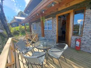 um pátio com uma mesa e cadeiras em um deck em Cabañas Atardecer Fandango em Chaitén