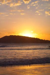 a sunset on the beach with a hill in the background at relajate en buzios in Búzios