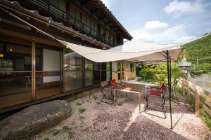a patio with a white umbrella next to a building at A luxurious accommodation experience surrounded by nature in Okazaki