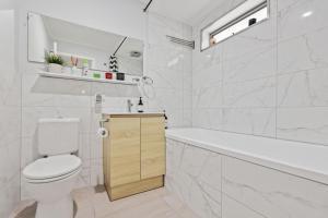 a white bathroom with a toilet and a bath tub at 36 Lacrington St, Goolwa Beach in Goolwa South +14 photos
