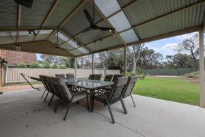 a patio with a table and chairs under a roof at 36 Lacrington St, Goolwa Beach in Goolwa South