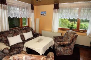 a living room with a couch and a table and windows at Ferienhaus Am Weiher in Waltershausen +14 photos
