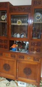a large wooden cabinet with glass doors with dishes in it at Margiii apart in Augusta