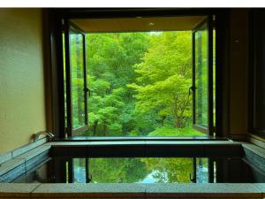 Una ventana en un baño con vista a un bosque. en 箱根薫風, en Hakone
