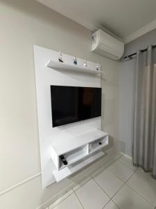 a living room with a tv on a white wall at Loft BC ESTÚDIO Centro in Balneário Camboriú
