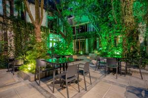 a restaurant with a green wall with tables and chairs at Alko Hotel Casa Nispero in Cali