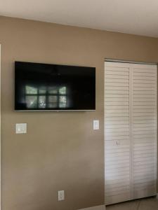 a room with a television on the wall and a closet at Tropical Jungle Bugelow in Naples