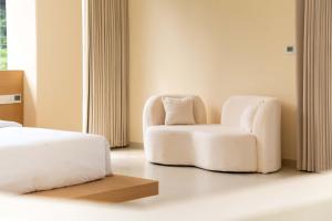 een slaapkamer met een witte stoel en een bed bij Yi Zhan Mountain Homestay in Xingping