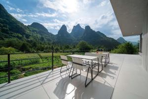 een balkon met een tafel en stoelen en bergen bij Yi Zhan Mountain Homestay in Xingping