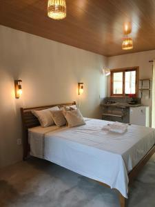 a bedroom with a large white bed with two pillows at Há Mar Chalés Corumbau in Prado