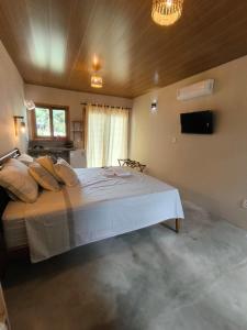 een slaapkamer met een groot wit bed in een kamer bij Há Mar Chalés Corumbau in Prado