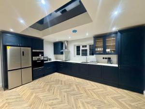 a large kitchen with blue cabinets and white appliances at Richard guest house in Roydon +37 photos