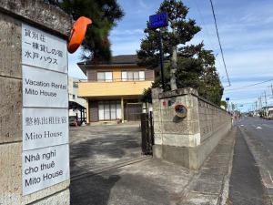 a sign on the side of a street with a building at 一棟貸しの宿 貸別荘 水戸ハウス Vacation Rental Mito House! Location is 1-2-55 Kanemachi Ibaraki Prefecture 場所は茨城県水戸市金町1-2-55です ドア横のキーボックスの番号はご予約後に,チェックイン情報を見る,をご覧下さい in Mito