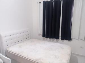 a small bed in a room with a window at Aconchegante in Peruíbe