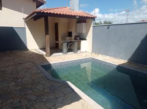 a swimming pool with a gazebo next to a house at Aconchegante in Peruíbe