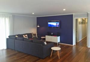 a living room with a couch and a tv on a wall at Eastgarth in Venus Bay