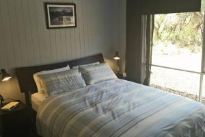 a bed in a bedroom with a large window at Eastgarth in Venus Bay
