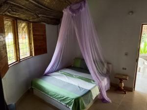 a bed with a canopy in a room with windows at ECOHOTEL LAS FLORES Econativo in Isla Grande