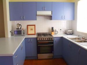 a kitchen with blue cabinets and a stove and a microwave at Emada Venus Bay in Venus Bay