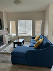 ein Wohnzimmer mit einem blauen Sofa und einem Tisch in der Unterkunft Luxurious & Spacious 4-Bedroom Vacation Home in Edmonton
