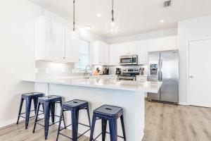 una cucina con mobili bianchi e un bancone con sgabelli di Cassine Dream a Santa Rosa Beach