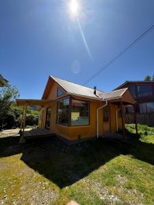 a small yellow house with the sun in the sky at Cabañas dunn in Puerto Cisnes