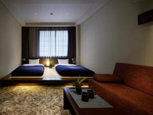una habitación de hotel con dos camas y un sofá en Minn Kanazawa, en Kanazawa