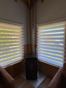 a living room with two windows with blinds at Cabañas dunn in Puerto Cisnes