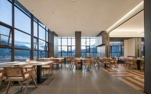 a restaurant with tables and chairs and large windows at Lijiang Gucheng District RIM Hotel in Lijiang
