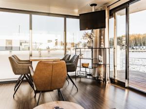 a dining room with a table and chairs and large windows at Floating Houseboat in Peenemünde in Peenemünde