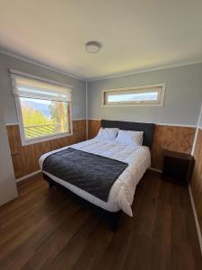 a bedroom with a large bed and two windows at Cabañas dunn in Puerto Cisnes
