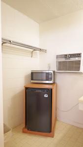 a small kitchen with a microwave and a refrigerator at Sawmill Lodges Motel in Hennessey