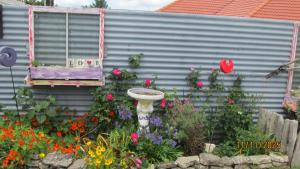 a garden with a bird bath in the middle of flowers at Cozy Haven - Waihi in Waihi