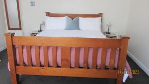 a wooden bed with white sheets and pillows on it at Cozy Haven - Waihi in Waihi +5 photos