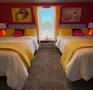 ein Schlafzimmer mit zwei Betten mit gelben und roten Wänden in der Unterkunft Casa Amor Texas A Vibrant Villa near BS&W with King Bed in Temple