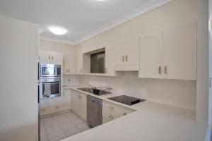 Nautilus 2 - Ground Floor Unit في هاوكس نيست: مطبخ أبيض مع خزائن بيضاء وأجهزة