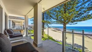 a view of the beach from the balcony of a house at Beachfront Breeze - Family Getaway By Holidayco in The Entrance