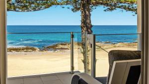 a view of the beach from the balcony of a house at Beachfront Breeze - Family Getaway By Holidayco in The Entrance +12 photos