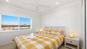 a white bedroom with a bed and a window at Beachfront Breeze - Family Getaway By Holidayco in The Entrance